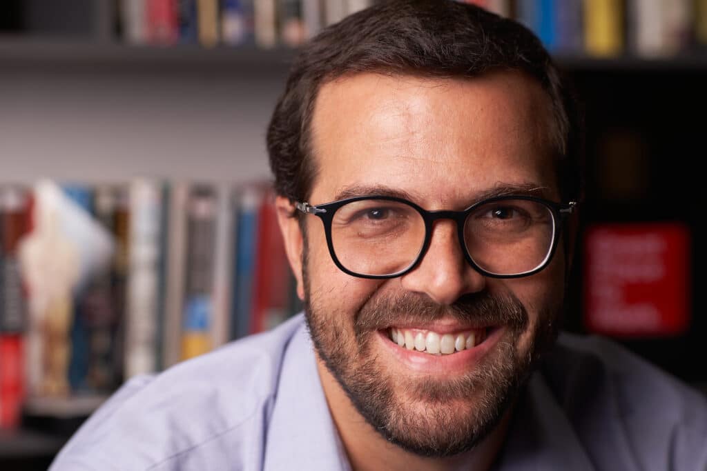 Retrato de um homem branco de óculos de grau sorrindo